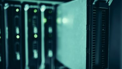 Close de racks de servidores em um data center moderno, com iluminação azul e indicadores luminosos.