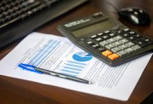 Calculadora, relatório financeiro e caneta sobre uma mesa, representando análise e controle orçamentário.