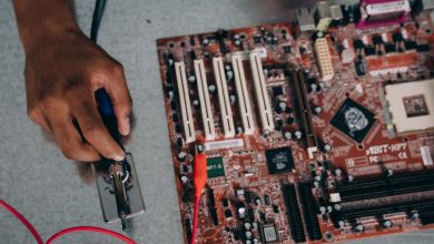 Engenheiro solda componentes de uma placa-mãe em um laboratório de tecnologia.